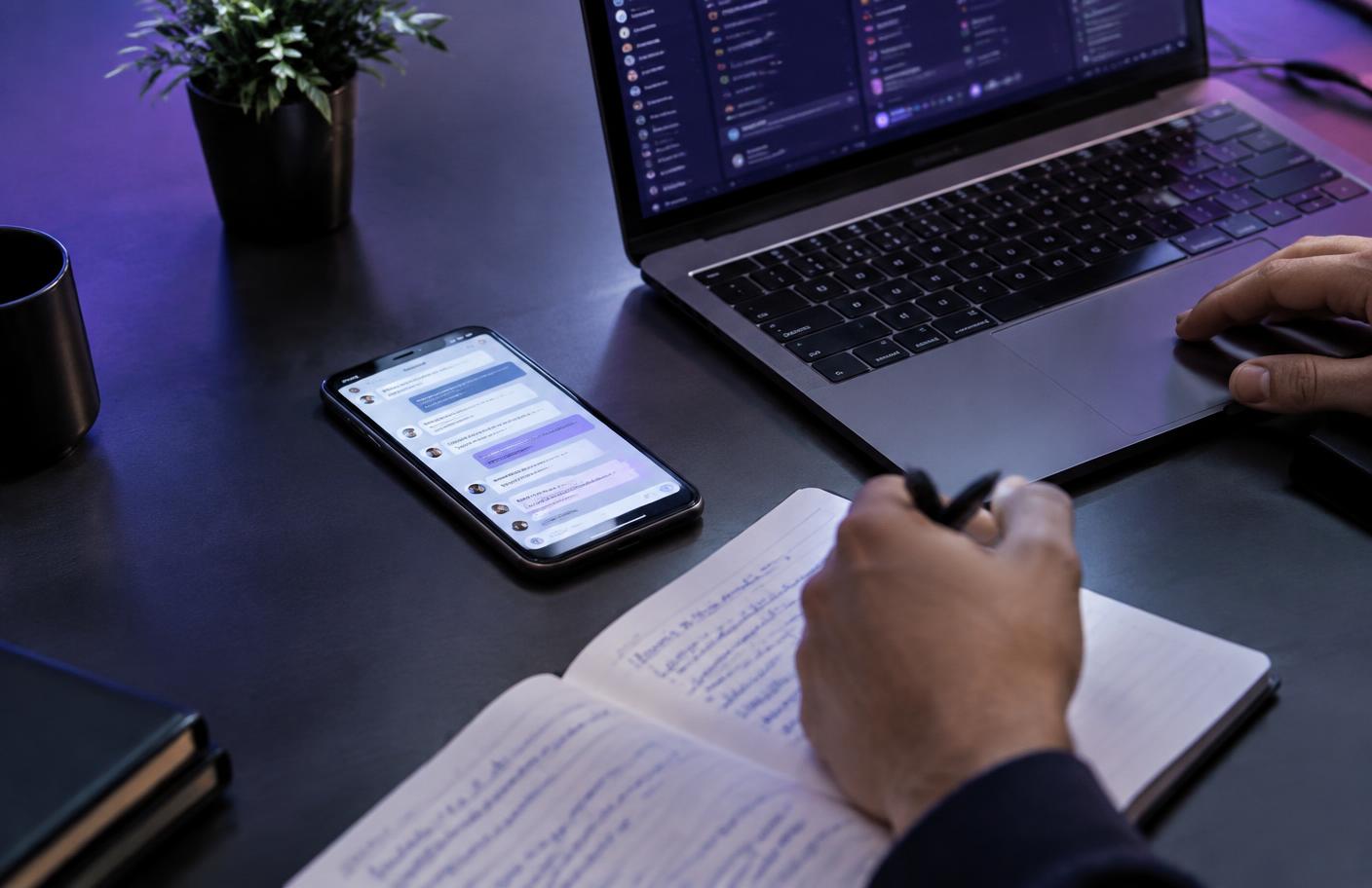 Marketing strategist planning customer messages beside a laptop and smartphone.